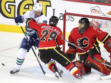 Calgary Flames goalie Jonas Hiller kept an eye on the puck as defenceman Deryk Engelland cleared  Vancouver Canucks left winger Daniel Sedin away from the crease during second period NHL Game 3 playoff action at the Scotiabank Saddledome in Calgary on April 19, 2015.