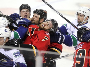 Flames defenceman TJ Brodie, centre, had his head pulled back as members of the Calgary Flames and Vancouver Canucks scrapped during first period NHL playoff action in game 4 of the series at the Scotiabank Saddledome in Calgary on April 21, 2015.