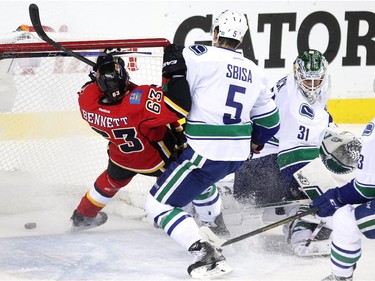 Calgary Flames centre Sam Bennett, left, was driven into the net by Vancouver Canucks defenceman Luca Sbisa as goalie Eddie Lack watched the puck slide into the net during first period NHL playoff action in game 4 of the series at the Scotiabank Saddledome in Calgary on April 21, 2015.