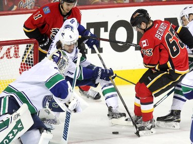 Calgary Flames centre Sam Bennett, right, fought to get possession of the puck as Vancouver Canucks defenceman Christopher Tanev bobbled the puck near the net of goalie Eddie Lack during first period NHL playoff action in game 4 of the series at the Scotiabank Saddledome in Calgary on April 21, 2015.