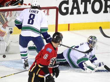 Vancouver Canucks goalie Eddie Lack and defenceman Christopher Tanev watched as a shot by Calgary Flames left winger Johnny Gaudreau slipped past Lack for the opening goal of the game during first period NHL playoff action in game 4 of the series at the Scotiabank Saddledome in Calgary on April 21, 2015.