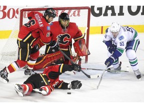 Calgary Flames defenceman Kris Russell, on ground, blocked a shot as teammates defenceman Dennis Wideman and goalie Jonas Hiller kept an eye on the puck and Vancouver Canucks centre Bo Horvat during second period NHL playoff action in game 4 of the series at the Scotiabank Saddledome in Calgary on April 21, 2015.