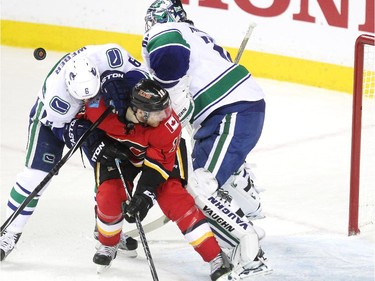 A shot by the Calgary Flames deflected off the back of Vancouver Canucks defenceman Yannick Weber as he tangled with Calgary Flames centre Matt Stajan outside the crease of Vancouver Canucks goalie Ryan Miller during second period NHL playoff action in game 4 of the series at the Scotiabank Saddledome in Calgary on April 21, 2015.