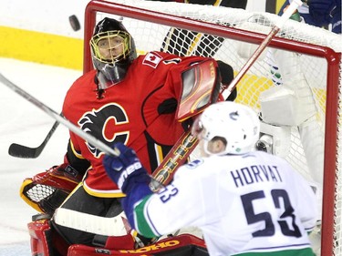 Calgary Flames goalie Jonas Hiller kept his eye on a flying puck as Vancouver Canucks centre Bo Horvat looked to tip it out of the air during third period NHL playoff action in game 4 of the series at the Scotiabank Saddledome in Calgary on April 21, 2015. The Flames defeated the Canucks 3-1 to take a 3-1 lead in the best of 7 series.