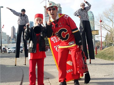 Colleen De Neve/ Calgary Herald CALGARY, AB --APRIL 22, 2015 -- Calgary hockey fans Alyssa Panei, 10, and her dad Tito Panei dressed in red with face paint and a hard hat as they showed off their playoff hockey fashion outside the Scotiabank Saddledome with members of the Green Fools dressed as referees on stilts on April 21, 2015 prior to game 4 of the playoffs between Calgary and Vancouver.  (Colleen De Neve/Calgary Herald) (For City story by Val Fortney) 00064508A SLUG: 0422-Flames Fans Fashion