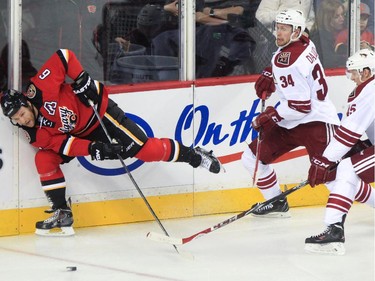 Calgary Flames defence Dennis Wideman and Arizona Coyote players Klas Dahlbeck and Andrew Campbell go after the puck at the Saddledome in Calgary on Tuesday, April 7, 2015.