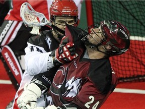 Calgary Roughnecks defenceman Curtis Manning, left, hassled Colorado Mammoth forward John Grant Jr. during second half NLL action at the Scotiabank Saddledome on January 25, 2014.
