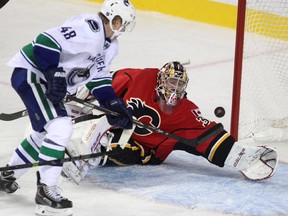 Calgary Flames goalie Brad Thiessen reached his glove hand to try to glove a shot by Vancouver Canucks centre Hunter Shinkaruk which was the third goal for the Canucks during third period NHL action at the Scotiabank Saddledome on September 25, 2014. The Canucks defeated the Flames 3-1.