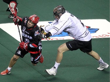 Calgary Roughnecks forward Shawn Evans looked to escape a check by Edmonton Rush transition defenceman Brett Mydske during first half NLL action at the Scotiabank Saddledome on April 10, 2015.