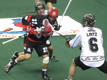 Calgary Roughnecks defenceman Andrew McBride got double teamed by Edmonton Rush Jeremy Thompson, left, and John Lintz during first half NLL action at the Scotiabank Saddledome on April 10, 2015.