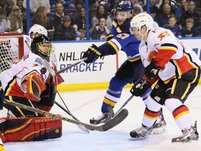 St. Louis Blues centre Marcel Goc, second from right, tries to knock an airborne puck past Calgary Flames goaltender Jonas Hiller during the first period of an NHL hockey game, Thursday, April 2, 2015 in St. Louis.