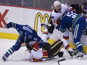 Vancouver Canucks' Brad Richardson (15) fights with Calgary Flames' Matt Stajan (15) as Vancouver Canucks right wing Derek Dorsett (51) fights with Calgary Flames defenseman Deryk Engelland (29) during the third period of game 2 of the NHL Western Conference first round playoff hockey series in Vancouver, B.C. Friday, April 17, 2015.