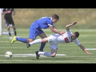 Foothills FC player Yoann Promonet, centre, is pushed to the ground at Hellard Field in Calgary on Sunday, May 17, 2015. The Foothills FC under-23 team won over the Puget Sound Gunners, 2-1, in their home opening game.