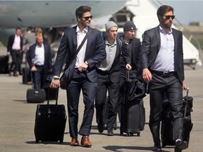 Flanked by teammates, Calgary Flames left winger Johnny Gaudreau, centre, walks to the terminal after the team returned to Calgary on Monday afternoon after losing the first two games of their series against the Anaheim Ducks.