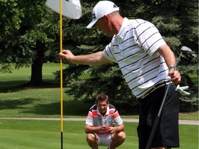 Jamie Welder studies the lay of the green as Kevin Temple clears the flag on the 16th hole at the Calgary Golf and Country Club during the finals of the Calgary Golf Association's Rileys best ball tournament last June. The defending champs are back and have home course advantage throughout the 2015 tourney.