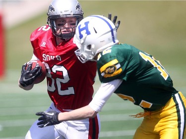 Slotback Bennett Thompson of George Macdougall high school in Airdire tries to hold off defensive back Tanner Olstad of Hunting Hills in Red Deer,  at the Alberta Senior Bowl all-star game between South all-stars and North all-stars at McMahon Stadium in Calgary.