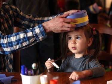 John Kelly helps his daughter Elizabeth, 2, try on her pillbox cap she created on Mountie Day that celebrates the creation of Northwest Mounted Police from 1873, at Fort Calgary on May 18, 2015.
