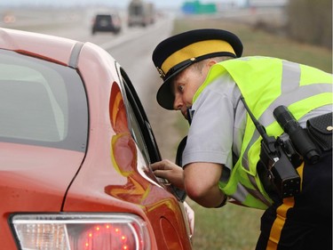 RCMP Sgt. Darrin Turnbull gives a speeding ticket to a driver on the Trans- Canada Highway west of Calgary on Thursday. The driver was given a $274 ticket for driving 143 km/h in the 110 km/h zone.