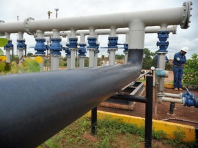 An engineer of Canadian oil company Pacific Rubiales stands by pipelines that carry heavy crude oil extracted from several wells (clusters) of Colombia's main oilfield Rubiales, in Meta department, Colombia, on August 27, 2013.