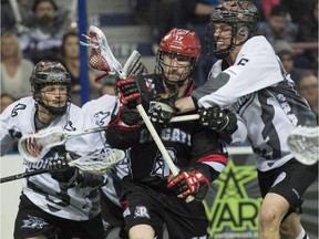Adrian Sorichetti and John Lintz of the Edmonton Rush, sandwich Curtis Dickson of the Calgary Roughnecks in National Lacrosse League action at Rexall Place in Edmonton.