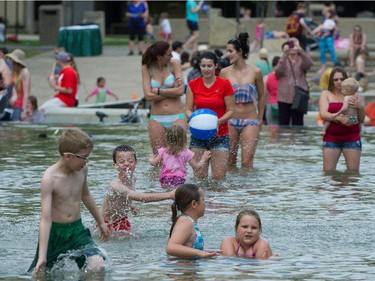 Children play in a pool as Premier Rachel Notley and her 11 cabinet ministers are sworn in on the legislature steps in Edmonton .