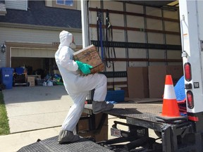 A man in a hazmat suit carries items from Star and Mark King's Sage Hill home. The house was trashed by Airbnb renters in late April and all the King's possessions need to be chemically treated and disinfected.