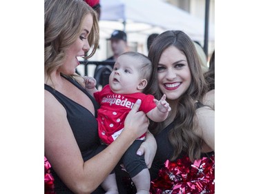 Calgary Stampeders Outriders get their photo taken with tiny fan Jessa Witherspoon, 5 months, at the annual Stampeders Fanfest at McMahon Stadium in Calgary, on May 23, 2015.