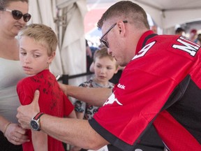 Calgary Stampeders quarterback Bo Levi Mitchell looks for a place to sign on the t-shirt of a young fan at the annual Stampeders Fanfest at McMahon Stadium on May 23. After a stellar 2014 season, the pivot is looking forward to further improvement in 2015.