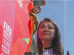 Kathy Hoang, who plays for Eastside Memorial Football Club, admires the FIFA Women's World Cup trophy as it stops in Calgary, on May 22, 2015, during its tour across Canada.