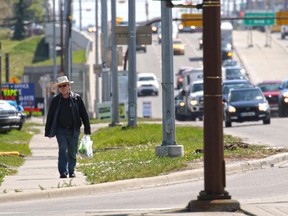 A pedestrian walks a  section of the sidewalk along Macleod Trail near Glenmore Trail.