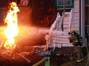 Calgary firefighters use water to cool a burning gas line as they extinguished a large fire in a home in Erinwoods on Wednesday evening.