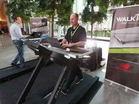 Devon Bolton, left and Ron Bettin, the founders of Fitneff, demonstrate how their new product WalkTop works. It's a portable desk that can be fitted onto a treadmill for people to work and exercise at the same time. The entrepreneurs held their demo in the lobby of Eighth Avenue Place on Wednesday.
