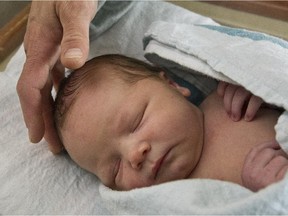 A newborn baby boy sleeps in his hospital crib.