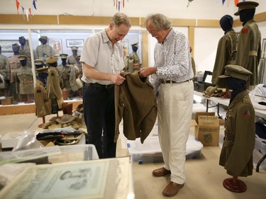 Victor Taboika, left, and Paul Squires look over one of the many World War 1 uniforms from his private collection that will be in the new temporary display at the Military Museums in Calgary on May 21, 2015.