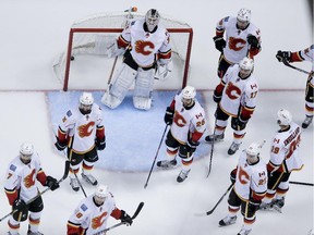 Members of the Calgary Flames look on as Anaheim Ducks celebrate Corey Perry's game-winning goal during overtime on Sunday night.