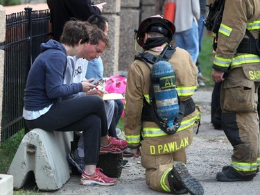 Residents forced out by a fire give info to firefighters.