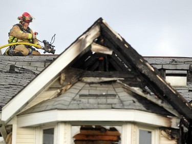 Colleen De Neve/ Calgary Herald CALGARY, AB -- MAY 26, 2015 -- A Calgary Fire Fighter sat on the peak of the roof as he worked to extinguish hot spots following a 2 alarm fire at a four-storey condo building in the 2200 block of 1st Street  SW  on May 26, 2015. At least four units received extensive damage. (Colleen De Neve/Calgary Herald) (For City story by Annalise Klingbeil) 00065591A SLUG: 0527-Mission Fire
