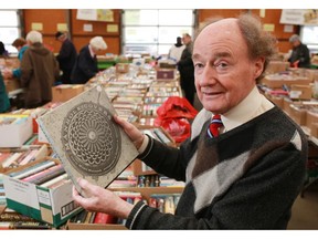 Gerry Morgan, the rare book expert,  at the Servant's Anonymous annual book sale, holds a unique photography book on manhole covers on Friday, May 15, 2015.