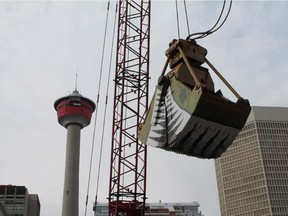 The clamshell bucket being used to excavate the future site of the Telus Sky building hangs from its crane with the Calgary Tower in the background on May 26, 2015.