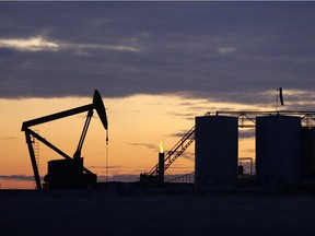 The sun begins to rise behind a pump jack and oil storage tanks near Williston, N.D.