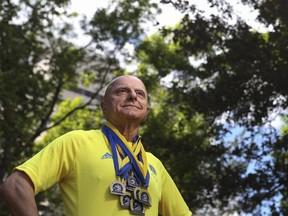 Victor Petrovic poses for a photo with all his 10 medals from the Boston Marathon in Calgary, on June 5, 2015. (Crystal Schick/Calgary Herald)