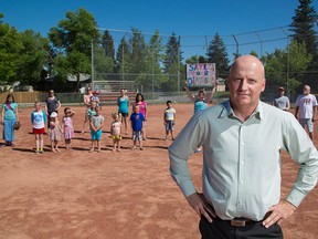 Tom Kaluzny poses along with members of the Fairview community opposed to having a community garden installed on a baseball diamond next to the Fairview Community Centre in Calgary on Monday, June 8.