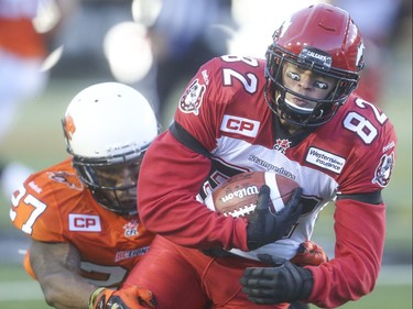 Calgary Stampeder wide receiver Cory Mitchell, centre, attempts to avoid a tackle by B.C. Lions defensive back Darious Lane at McMahon Stadium in Calgary on Friday, June 12, 2015. The Calgary Stampeders won over the B.C. Lions, 20-6, at the end of the the first pre-season exhibition game for the team.