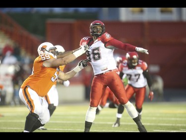 B.C. Lion centre Matthew Norman, left, pulls down Calgary Stampeder defensive lineman Demonte' Bolden at McMahon Stadium in Calgary on Friday, June 12, 2015. The Calgary Stampeders won over the B.C. Lions, 20-6, at the end of the the first pre-season exhibition game for the team.