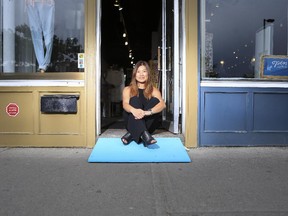 Hwa Kim, coordinator of the Ramp It Up project, sits in a Kensington store's doorway on June 23, 2015 with a  brightly coloured ramp, designed to increase accessibility at single stepped Calgary store fronts.