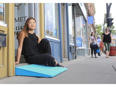Hwa Kim, coordinator of the Ramp It Up project, sits in a doorway with one of the brightly coloured ramps that will be used at several businesses in Inglewood and Kensington to make wheeled entry more accessible in Calgary, on June 23, 2015.