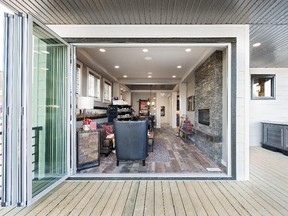 The rear patio with NanaWall opening from the great room, and an outdoor hot tub on the deck, in the Stampede Rotary Dream Home in 2015 by Homes by Avi.