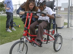 Nathan Maloney-Blake, centre, gets ready to ride a bicycle designed for children with disabilties at the Janice McTighe Centre in Calgary on Tuesday, May 26, 2015. The custom modified bicycles provide opportunities for young children with disabilities at the centre to ride with their friends.