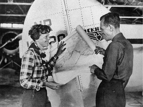 In this undated photo, aviator Amelia Earhart, left, and navigator Fred Noonan pose with a map of the Pacific Ocean showing the planned route of their round-the-world flight. (AP Photo)
