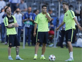 Barcelona's Lionel Messi, Luis Suarez and Gerard Pique, from left, laugh during a training session at the Olympic stadium in Berlin  Friday, June 5, 2015 on the eve of the soccer Champions League final between Juventus Turin and FC Barcelona on Saturday.